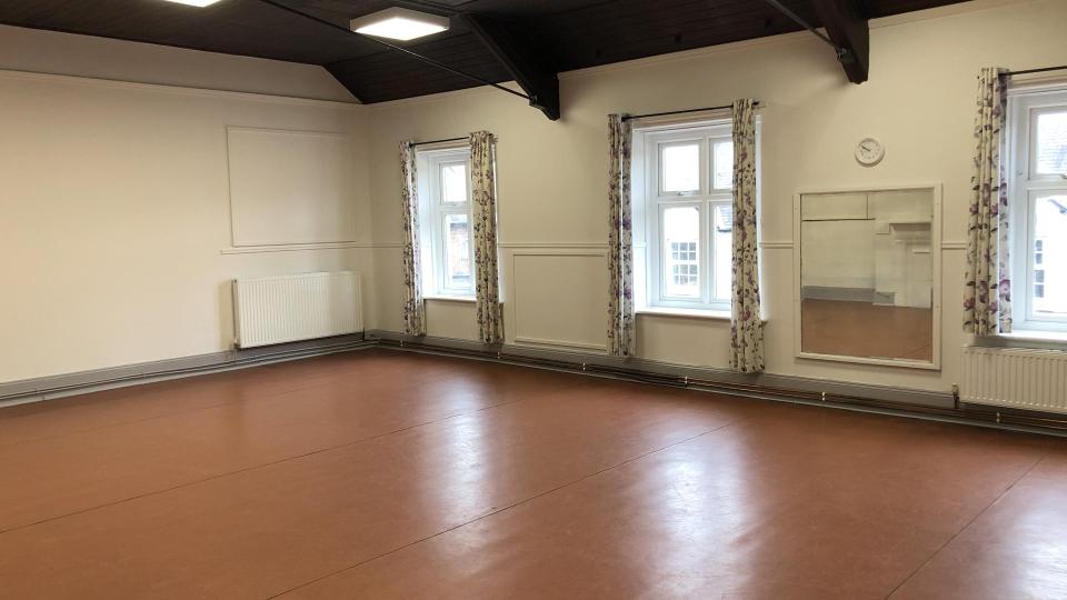 A large room with sliding doors leading to additional space and a small kitchen.  Access by staircase.
