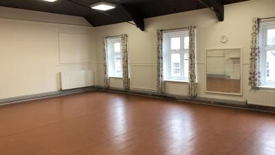 A large room with sliding doors leading to additional space and a small kitchen.  Access by staircase.